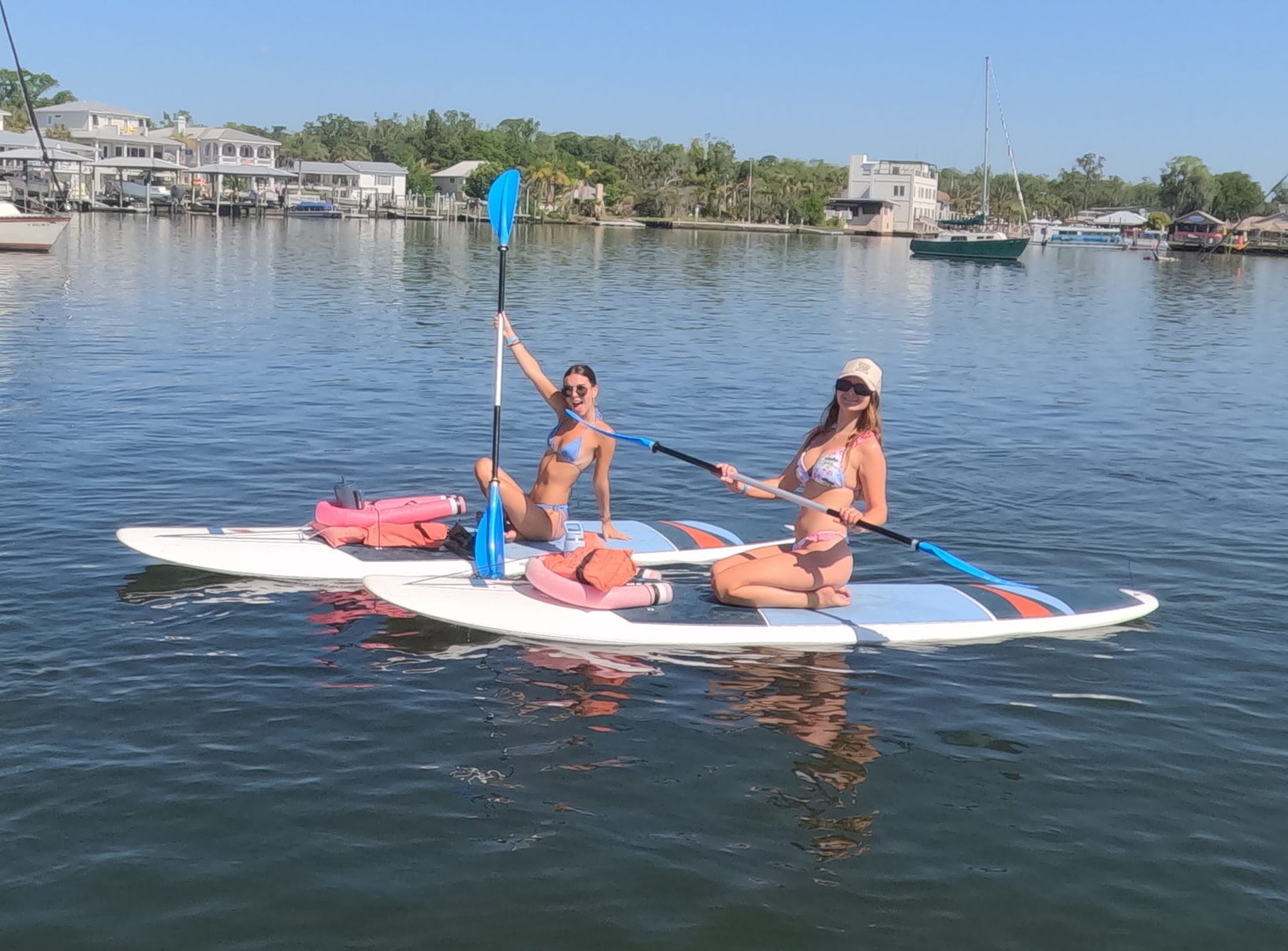 Two people seated on paddleboards on calm water near the shoreline